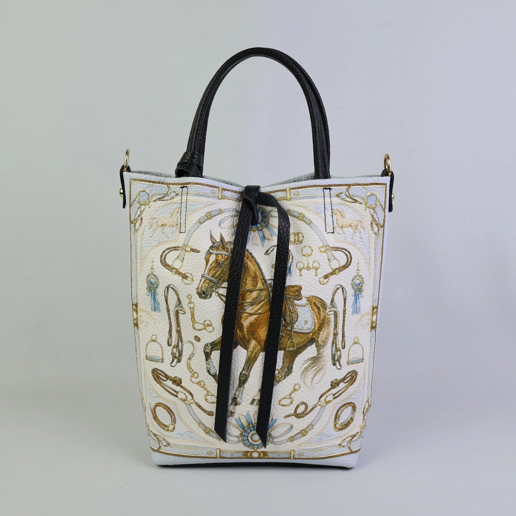 Borsa a mano in pelle bianca con stampa artistica di un cavallo marrone in stile equestre, motivi ornamentali con staffe, briglie e doppi manici neri.