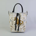 Borsa a mano in pelle bianca con stampa artistica di un cavallo marrone in stile equestre, motivi ornamentali con staffe, briglie e doppi manici neri.